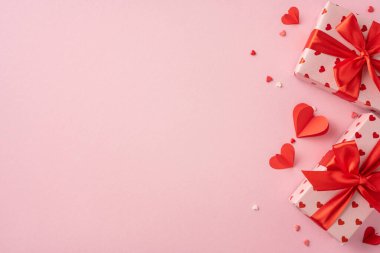 Romantik Sevgililer Günü sahnesinde güzel paketlenmiş hediye kutuları, kırmızı kurdeleler ve yumuşak pembe arka planda kalp süslemeleri, sevgi ve sevgiyi ifade etmek için mükemmel.