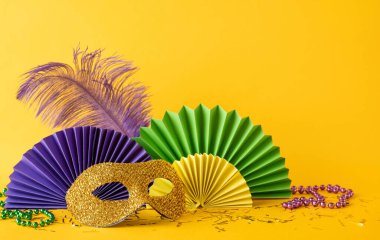 Mardi Gras şenliklerini sembolize eden yeşil ve mor vantilatör süslemeleriyle dekoratif altın maske