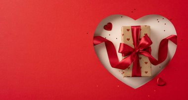 Kırmızı kurdeleli bir Sevgililer Günü hediyesi kutusu. Kırmızı bir arka planda kalp şeklinde bir kesiğin içine yerleştirilmiş. Aşkı ve romantizmi simgeliyor.