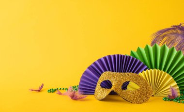 Parlak altın bir maske, canlı kağıt fanatikler ve Mardi Gras kutlamalarının canlı özünü temsil eden yeşil boncuklar içeren şenlikli bir yan manzara düzenlemesi.