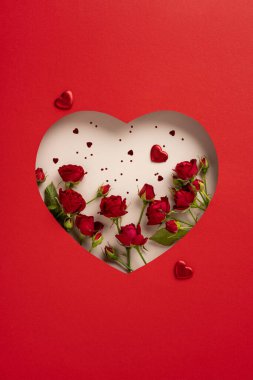 Kırmızı kalp şeklindeki kırmızı güllerin ve dekoratif kalplerin dikey dizilişi.