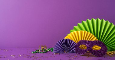 Mardi Gras 'nın renkli aksesuarları arasında parlak mor bir maske, şenlikli boncuklar ve mor bir arkaplanda sergilenen ve festivalin kutlayıcı özünü yakalayan kağıt kolyeler de var.