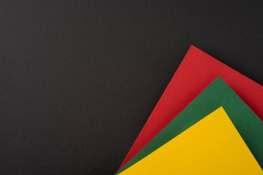 Siyah arka planda kırmızı, sarı ve yeşil renkli renkli kağıtlar var.