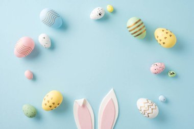 Renkli pastel Paskalya yumurtaları pembe tavşan kulaklarının etrafına dizilmiştir.