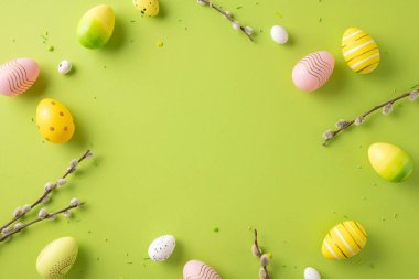 Canlı yeşil bir zemin üzerinde bahar dalları olan renkli Paskalya yumurtalarının neşeli görüntüsü