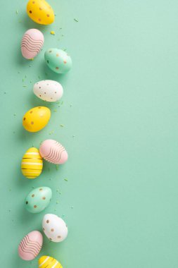 Süslü bir şekilde pastel renklere boyanmış Paskalya yumurtaları dikey yeşil bir zemine yerleştirilmiş.