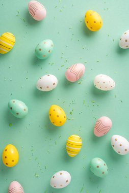 Paskalya dikey yumurtaları farklı renklerde ve desenlerde yeşil arka planda yayılmış.