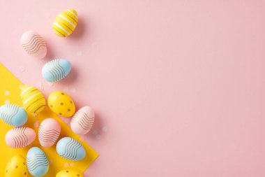 Renkli dekoratif Paskalya yumurtaları yumuşak pembe bir arka plan köşesinde dizilmiş bahar kutlamalarını çağrıştırıyor.