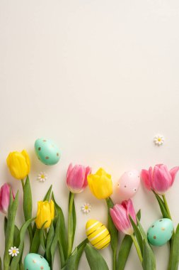 Pastel dekoratif paskalya yumurtaları ve papatya çiçekleri ile parlak dikey sarı ve pembe laleler arka planda bahar temalı bir kompozisyon oluşturur.