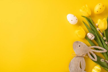 Yellow Easter-themed composition featuring floral tulips, decorated eggs, and festive wooden bunny. clipart