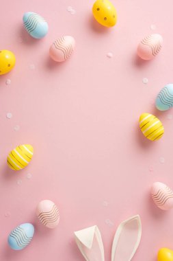 Renkli dikey Paskalya yumurtaları ve pembe arka planda tavşan kulakları, kutlamalar için mükemmel.