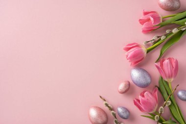Spring-themed arrangement of pink tulips, speckled Easter eggs, and pussy willow branches on a pastel pink setting, evoking Easter and seasonal decoration vibes