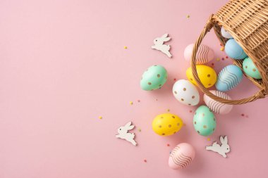 Hasır sepet, canlı boyanmış yumurta ve yumuşak pembe arka planda tavşan aksanlı Paskalya süslemeleri neşeli ve neşeli tatil havalarını çağrıştırıyor.