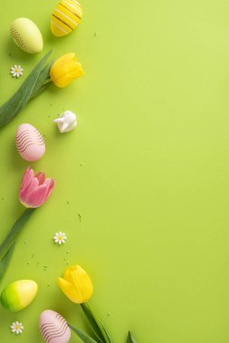 Yeşil bir yüzeye düzgünce yerleştirilmiş laleler ve dekoratif paskalya unsurlarıyla mevsimsel dikey bileşim