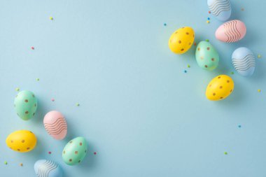 Renkli dekoratif Paskalya yumurtaları neşeli bir tema için yumuşak mavi pastel arka planda düzenlenmiştir.