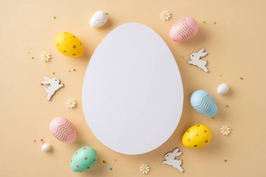 Renkli dekorasyonlar, tavşanlar ve çiçeklerle çevrili boş beyaz bir yumurta içeren Paskalya temalı kompozisyon