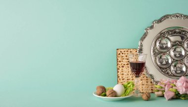 Geleneksel bir Hamursuz Bayramı yemeği seti. Yumuşak yeşil ışık altında gümüş bir Seder tabağı, matza ve sembolik eşyalar da dahil.