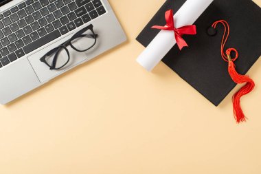 Mezuniyet kapanışı, bej arka planda bir diploma, mezuniyet şapkası ve dizüstü bilgisayar gösteriyor.