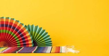 Parlak sarı arka planda kağıt yelpaze ve kumaş desenleri içeren şenlikli dekoratif öğeler
