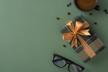 Yeşil yüzeye sarılı şık bir hediye kutusu kahve ve güneş gözlüğünün yanında özel bir kutlama, takdir ya da düşünceli bir an öneriyor.