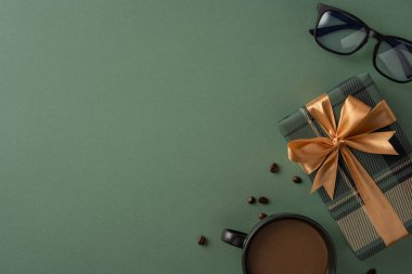 Kurdeleli hediye kutusu, kahve fincanı, güneş gözlüğü ve yeşil arka plan kutlama çağrıştırıyor.
