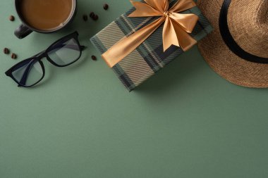 Kurdeleli hediye kutusu, şık şapka, kahve fincanı ve yeşil yüzeye yerleştirilmiş bardaklar.