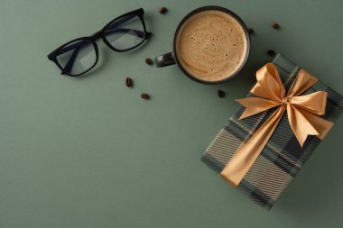 Altın kurdeleli zarif yeşil hediye kutusu, kahve fincanı ve gözlüklerle çevrili.