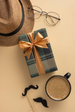 Bir hediye kutusu, şapka, fötr şapka, bardaklar ve kahve de dahil olmak üzere Babalar Günü unsurlarını gösteren ters sıcak tonlu görüntü minnettarlığı ve kutlamaları simgeliyor.