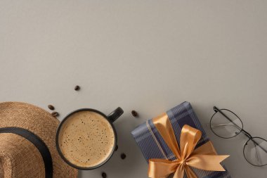 Bir fincan kahve, fiyonklu bir hediye kutusu, hasır şapka ve ev atmosferi için bej bir arka planda ayarlanmış gözlük içeren rahat bir kompozisyon.