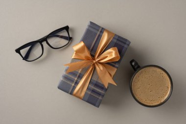 Samimi bir ortamda kurdele, kahve fincanı ve gözlüklü bir hediye kutusunun düzleşmesi.