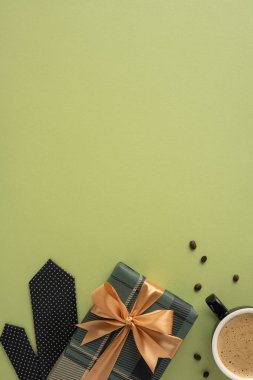 Kurdele, kahve fincanı ve dikey minimalist bir yüzeye kurulmuş dekoratif bir kravat ile sarılmış bir hediye.