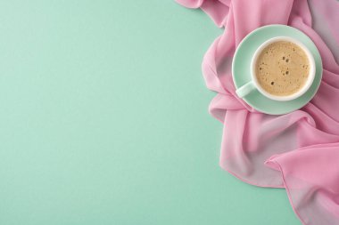 Yeşil arka planı olan pembe bir kumaşa yerleştirilmiş bir fincan kahvenin yer aldığı minimal estetik düzenek, basitlik, rahatlama ve kahve anlarının keyfini çıkarmak için sakin bir atmosfer çağrıştırıyor.