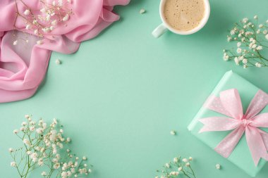 Nane ambalajlı bir hediye, narin çiçekler, pembe kumaş ve kahve içeren düz bir kompozisyon.