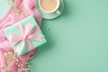 Yumuşak kurdeleli zarif bir hediye, bir fincan kahve, ve temiz yeşil ve pembe yüzeylere yerleştirilmiş narin çiçekler. Kutlamalar, minnettarlık ve özel durumlar için mükemmel.