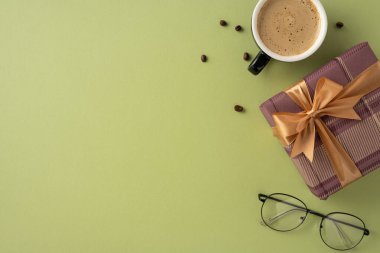 Yeşil zemin üzerinde kahve fincanı, hediye kutusu ve gözlük olan şık bir sahne.