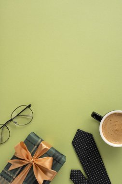 Sarılı Babalar Günü hediyesinin düz bir kompozisyonu vardı. Siyah benekli kravat, kahve ve bardaklar yeşil arka plana karşıydı.