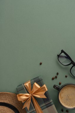 Yeşil bir yüzeye sarılı bir hediye, kahve, bardaklar ve şapkayla yatmış rahat bir atmosfer yaratıyor.