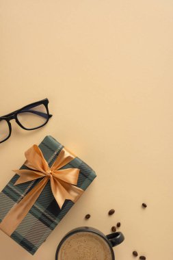 Gözlüklü bej dikey yüzey sahne, hediye paketi, kahve fincanı ve dağınık fasulye.