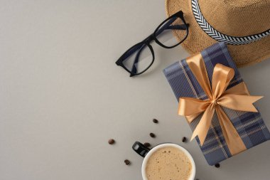 Süslü bir hediye kutusu, kahve fincanı, güneş gözlüğü ve hasır şapkayla süslenmiş zarif bir düzen. Rahatlama, kutlama ve şık bir yaşam sunar.