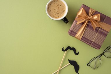 Babalar Günü tebrik kartı maketinde bir kahve fincanı, kurdele, gözlük ve yeşil arka planda yaratıcı bıyıklı hediye kutusu, samimi ve şenlikli bir atmosfer yayılıyor.
