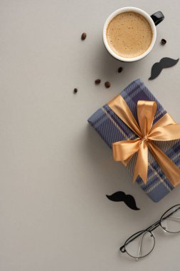 Altın kurdeleli bir hediye kutusunun dikey görüntüsü, bir kahve fincanı, ve Babalar Günü 'nü kutlayan aksesuarlar, neşeli ve neşeli bir hava yaratıyor.