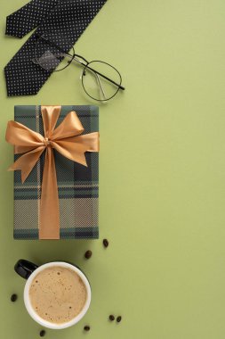 Hediye kutusu, kahve, gözlük ve kravat dikey yeşil bir yüzeye karşı sergileniyor.