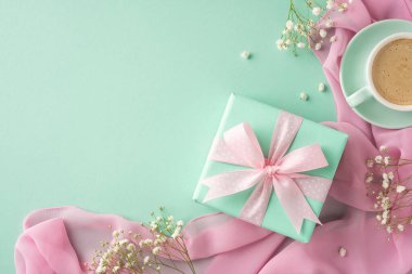 Pastel bir yüzeyde kahve fincanı eşliğinde bir kurdeleyle süslenmiş hediye kutusu, özel kutlamaları ve düşünceli anları sembolize eden hoş bir kompozisyon.