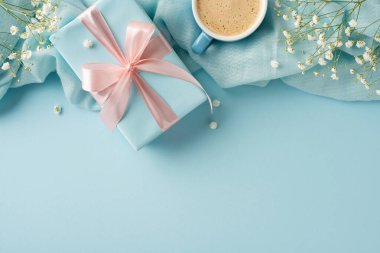 Pastel hediye kutusu, narin çiçekler ve rahatlatıcı mavi bir arka planda dizilmiş kahve fincanı.