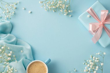 Yumuşak mavi bir zemin üzerinde bir kahve fincanı, hediye kutusu ve çiçeklerin yer aldığı sakin düz bir kompozisyon, kutlamalar ve huzurlu ortamlar için uygun.