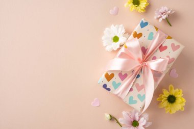 Süslü bir hediye kutusu. Etrafı papatya çiçekleri ve dağınık kağıt kalplerle çevrili. Kutlamalar ve Anneler Günü için mükemmel.