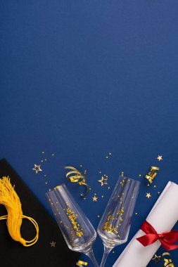 Mezuniyet dikey unsurları arasında bir kep, püskül, diploma, şampanya bardakları ve canlı mavi bir arka plana karşı hazırlanmış şenlikli konfeti, başarı, neşe ve kutlamalar yer alıyor.