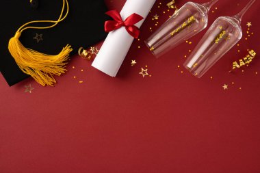 Mezuniyet şapkası, diploması ve şampanya kadehleri kutlama teması için ayarlandı. Kırmızı ve altın dekoratif unsurlar mezuniyet kutlamasının başarı atmosferini ve neşesini somutlaştırıyor.