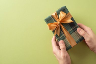 Elleri, altın kurdeleli ekose desenli bir hediye kutusu tutuyordu.