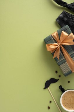 Dikey bir hediye kutusunun düz yatışı. Kahveli, yeşil bir yüzey üzerinde şık bir dekor.